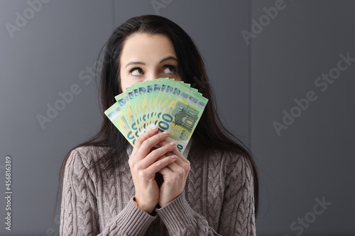 Young pensive woman holding lot of euro bills in front of her