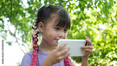Little beautiful girl with pink hair using the phone outdoors. Kids and Technology, smartphone, e-learning 