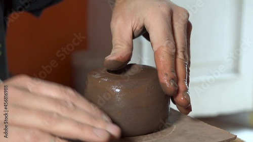 the strength of a potter's hands begin to primitively shape a block of red clay into a bowl photo