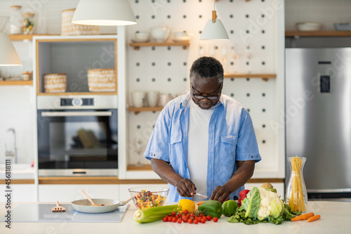 Senior African man standing in the kitchen and preparing a healthy dinner.