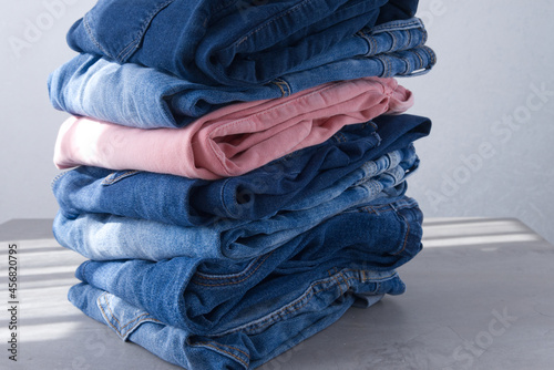 a pile of blue and pink jeans on a gray background. Close up (ID: 456820795)
