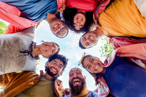 directly below portrait of multiethnic group of friends posing in the street outdoors laughing and having fun. diverse people celebrating life together enjoying happy holidays. lifestyle concept