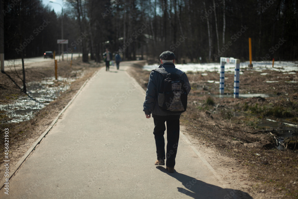 A man walks down the road in the park. A person in Russia steps to work.
