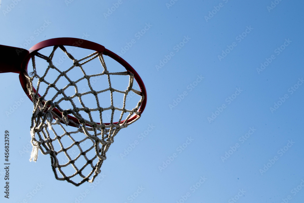 An orange basketball hoop against a blue sky