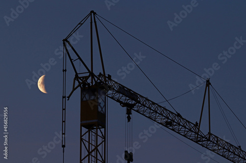 Schwarzarbeit im Baugewerbe. Ein Kran und der Mond am Nachthimmel