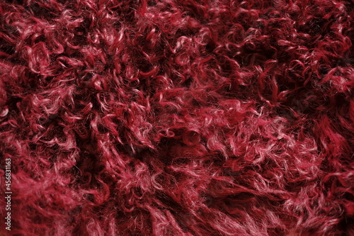 Fur background. Fluffy burgundy texture.Red real wool. Fur texture. Goat fur surface.