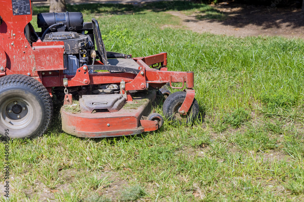 Obraz premium Utility worker in lawn mower gardener cutting the grass ride-on lawnmower