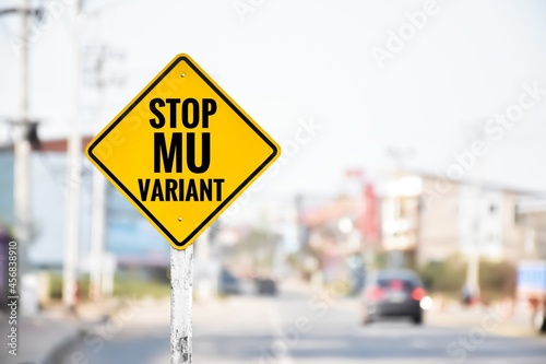 Traffic sign: ‘STOP MU VARIANT’ on cement pole beside the rural road with the blue and landscape background, copy space, concept for calling drivers to stop spreading new coronavirus now.