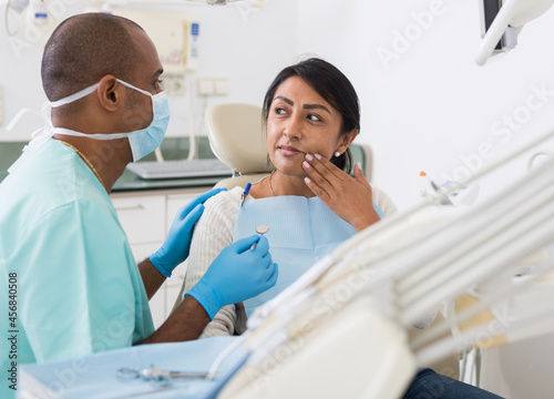 Woman patient talking to male dentist and complaining of toothache at dental clinic office