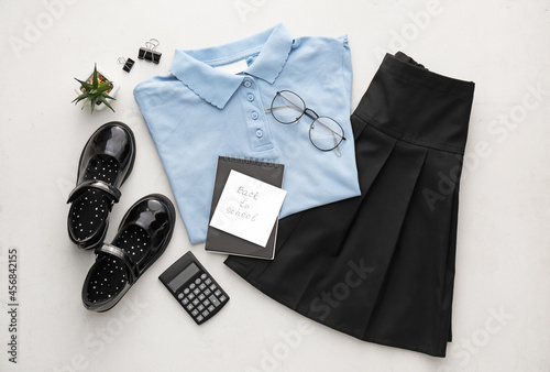 Foto Stylish school uniform, stationery, eyeglasses and paper sheet with text BACK TO