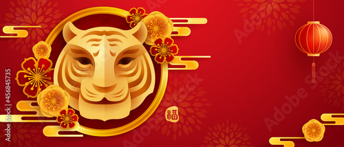 Happy Chinese New Year 2022. Year of The Tiger. Paper graphic cut art of golden tiger symbol and floral with oriental festive element decoration on red background.