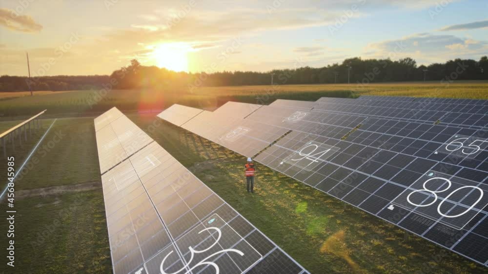 Engineer performs maintenance work on solar panels in green meadow with digital device. Animation, state of charge energy generation, green, climate-neutral energy source