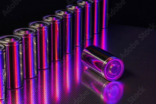 A pack of new modern high-capacity lithium-ion cells. A prototype of new batteries on a steel surface illuminated with red and blue light on a black background
