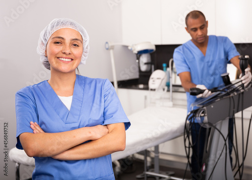 Portrait of skilled confident Latin American woman cosmetologist wearing blue overall in modern aesthetic medicine clinic