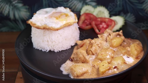 Authentic Thai Dish with Rice, Fried Egg and Massaman Potato with Tomatoes and Cucumber on the Side. Close up Rotating Dish Shot. photo