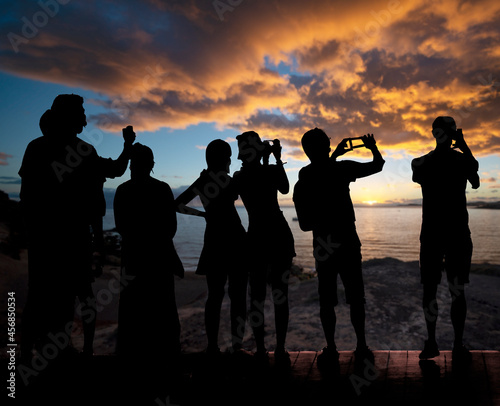 silhouette of people while photographing and admiring the sunset