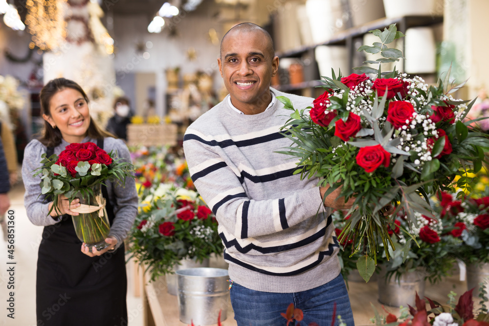 Fototapeta premium Friendly seller offering gift flower arrangement with roses to male buyer