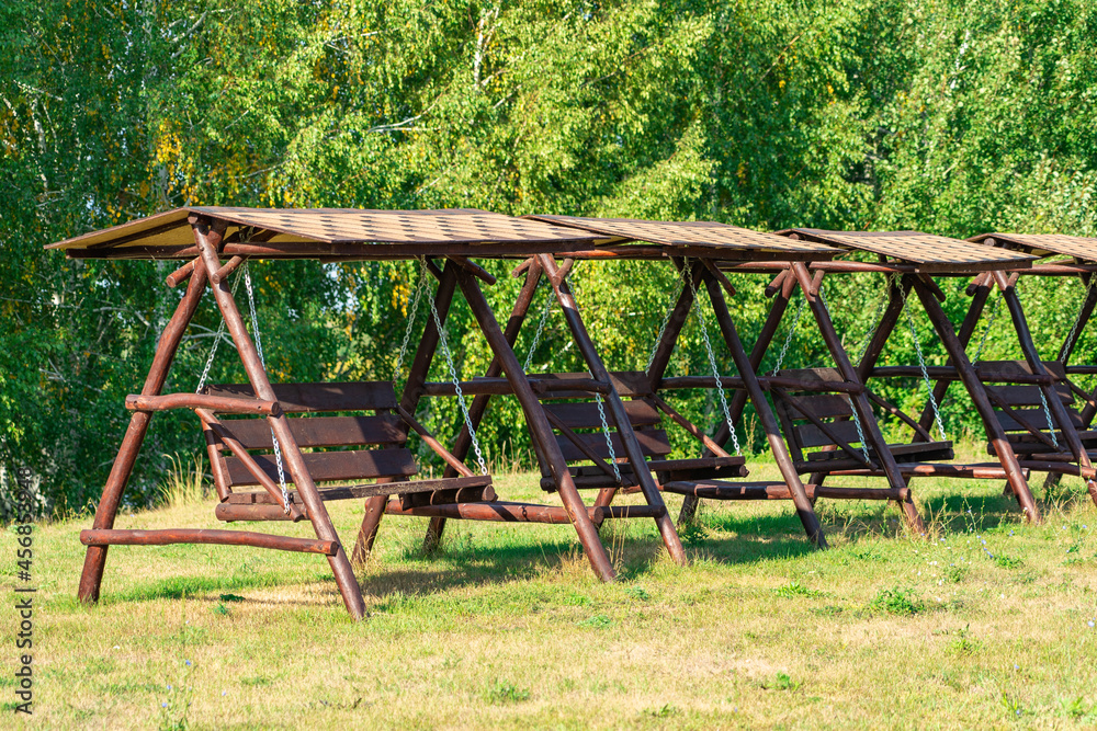A lot of wooden swings in a row stand on the street, the production of wooden swing benches