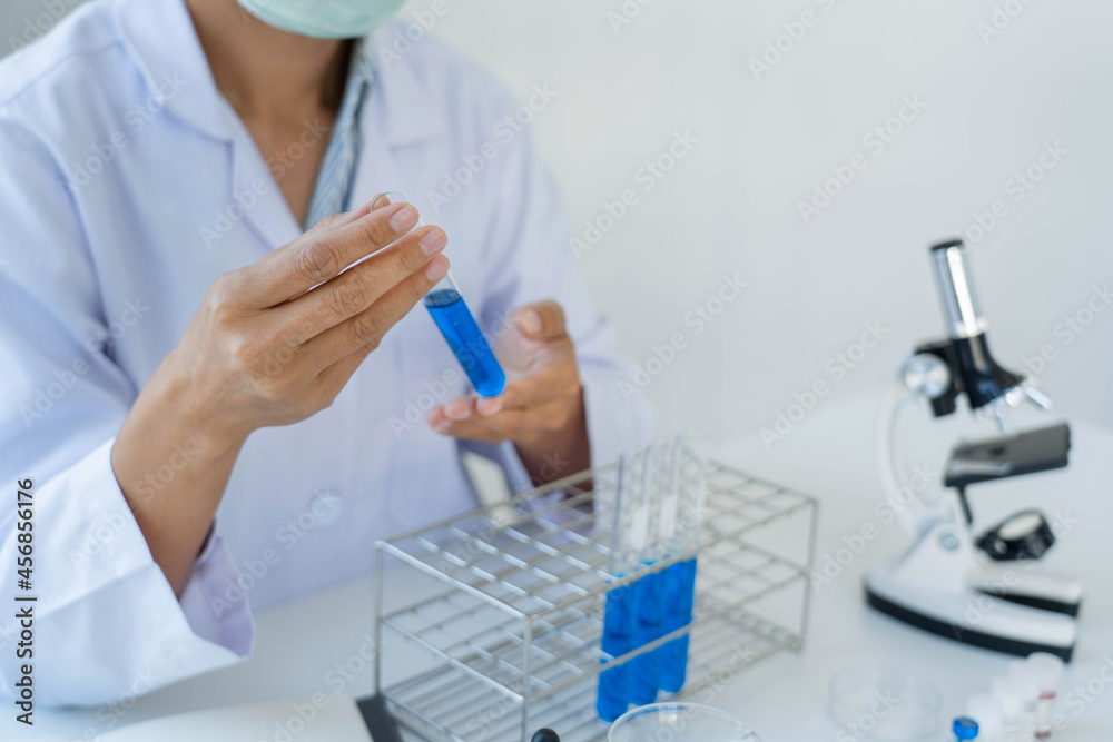 Scientist wear lab coat and protective wear are working with research or doing investigations with test tubes in experiment, Laboratory and development concept