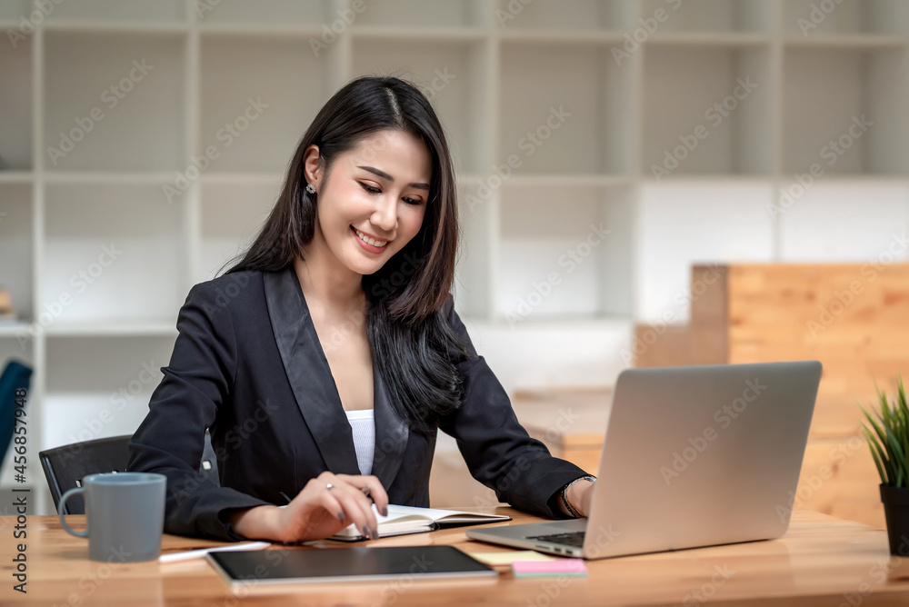 Beautiful Asian businesswoman work using a tablet and a laptop with documents placed at the office. Beautiful Asian businesswoman work using a tablet and a laptop with documents placed at the office.