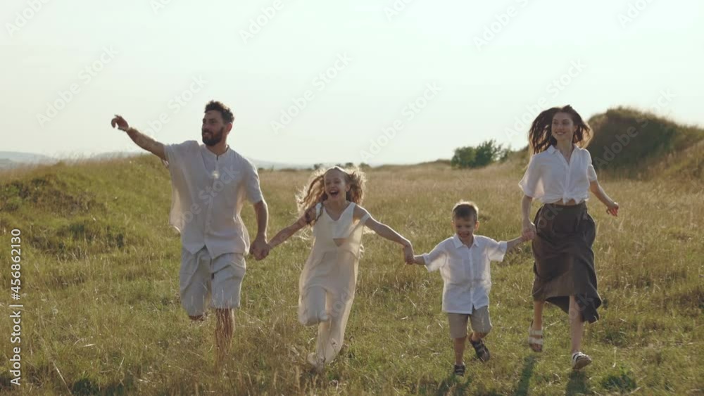 Loving parents with two kids taking fun on wild field