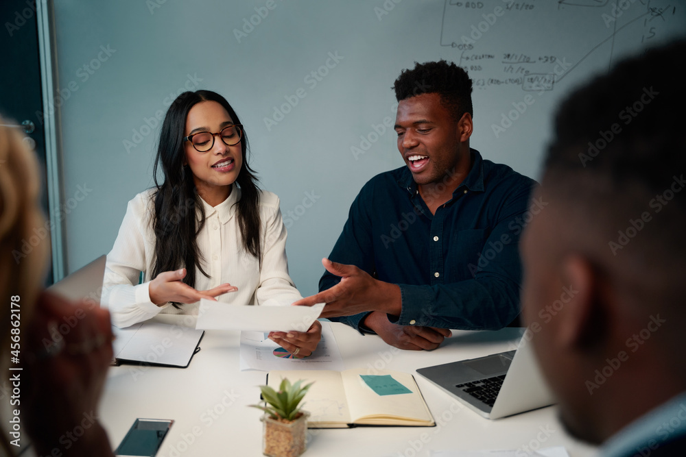© StratfordProductions - Multiethnic young man and woman having meeting at desk discussing the project in office