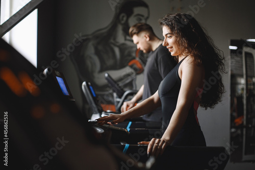 Woman is engaged in a gym with coach © hetmanstock2