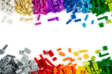 top view of border frame pile various colorful rainbow colored stackable plastic toy bricks isolated white panorama background.. childhood education construction concept
