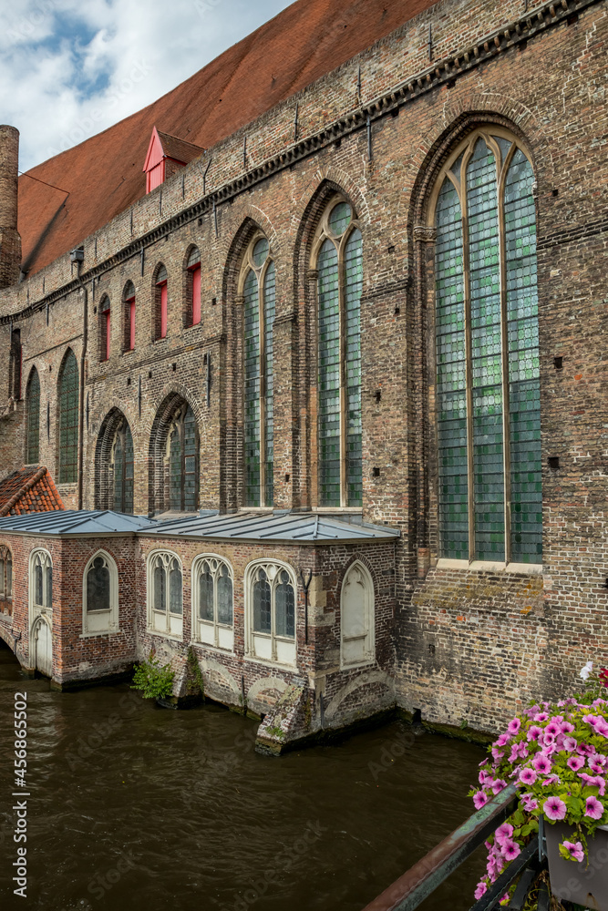 Old beautiful buildings around a canal in Bruges, Belgium. Flowers in the foreground