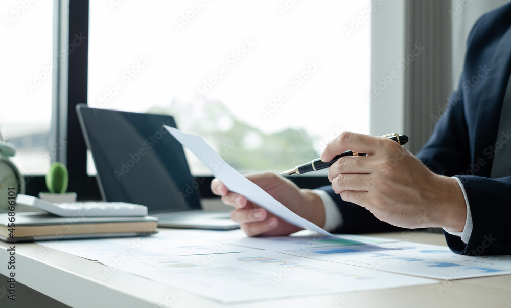 Fototapeta premium The hand of businessman sit at their desks and calculate financial graphs showing results about their investments, plan a successful business growth process