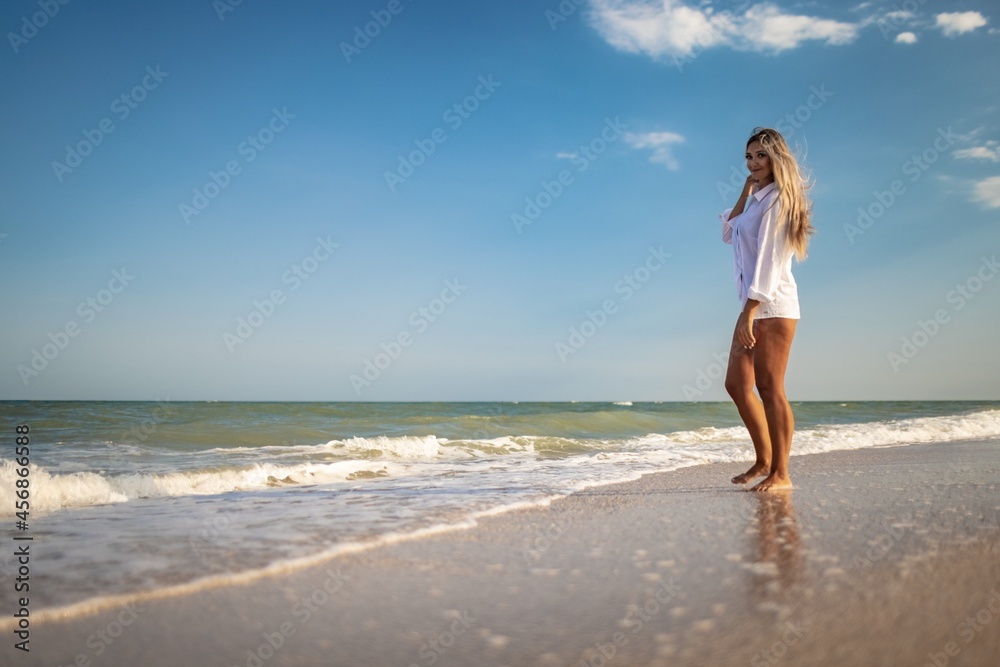A tanned girl in a blue swimsuit and a light shirt enjoys the summer at the seaside A tanned girl in a blue swimsuit and a light shirt enjoys the summer at the seaside