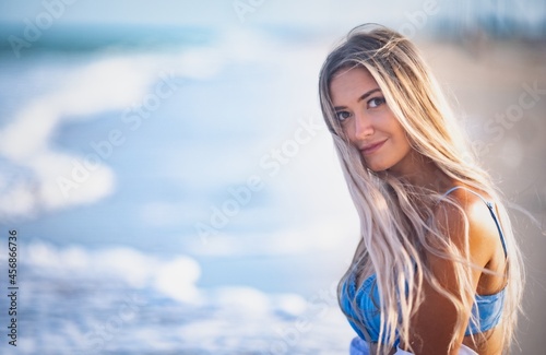 Portrait of a beautiful woman with blond hair in a blue swimsuit and white shirt © YouraPechkin
