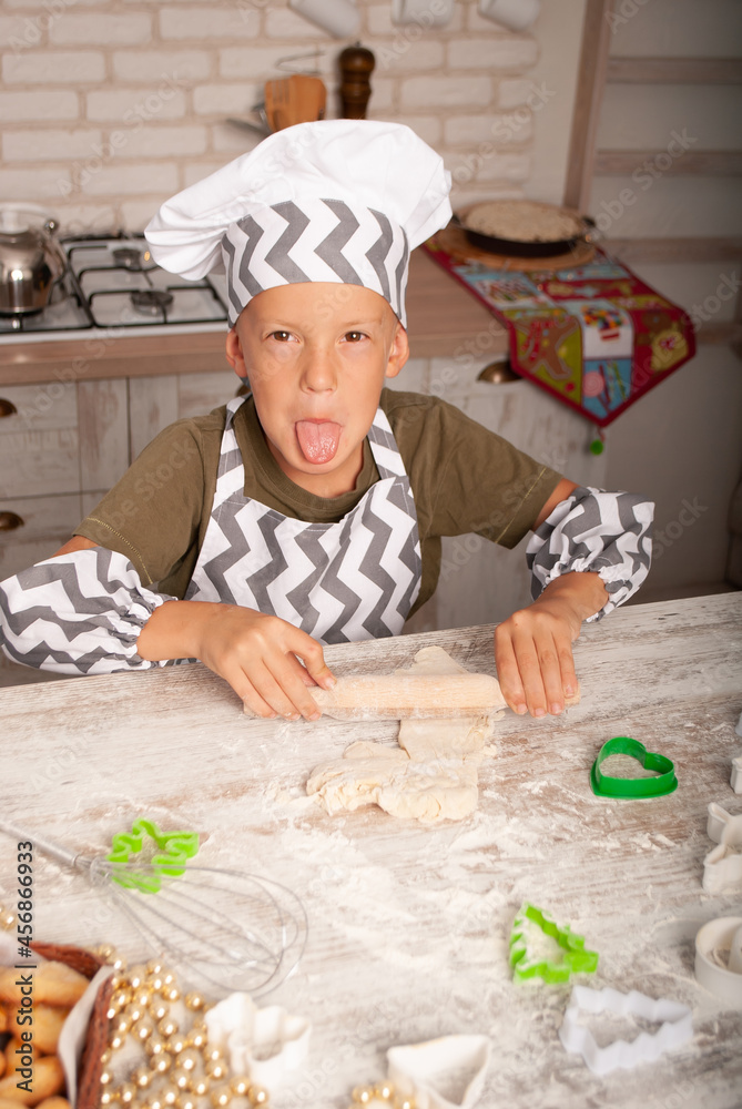 little boy writhing showing his tongue on camera while making Christmas cookies cutting out the tomoss of cook's day Christmas little boy writhing showing his tongue on camera while making Christmas cookies cutting out the tomoss of cook's day Christmas