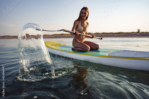 Close up of young woman sitting on a stand up paddle board