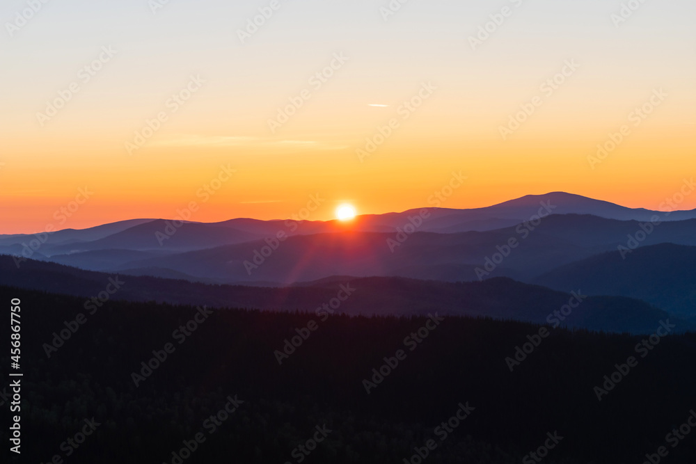 Beautiful and bright sunrise in the mountains. The sun's rays are breaking through from the tops of the misty mountains
