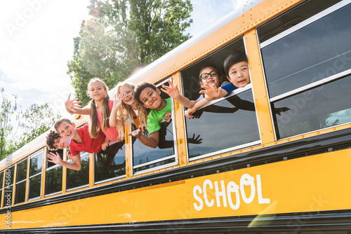 Group of young students attending primary school on a yellow school bus
