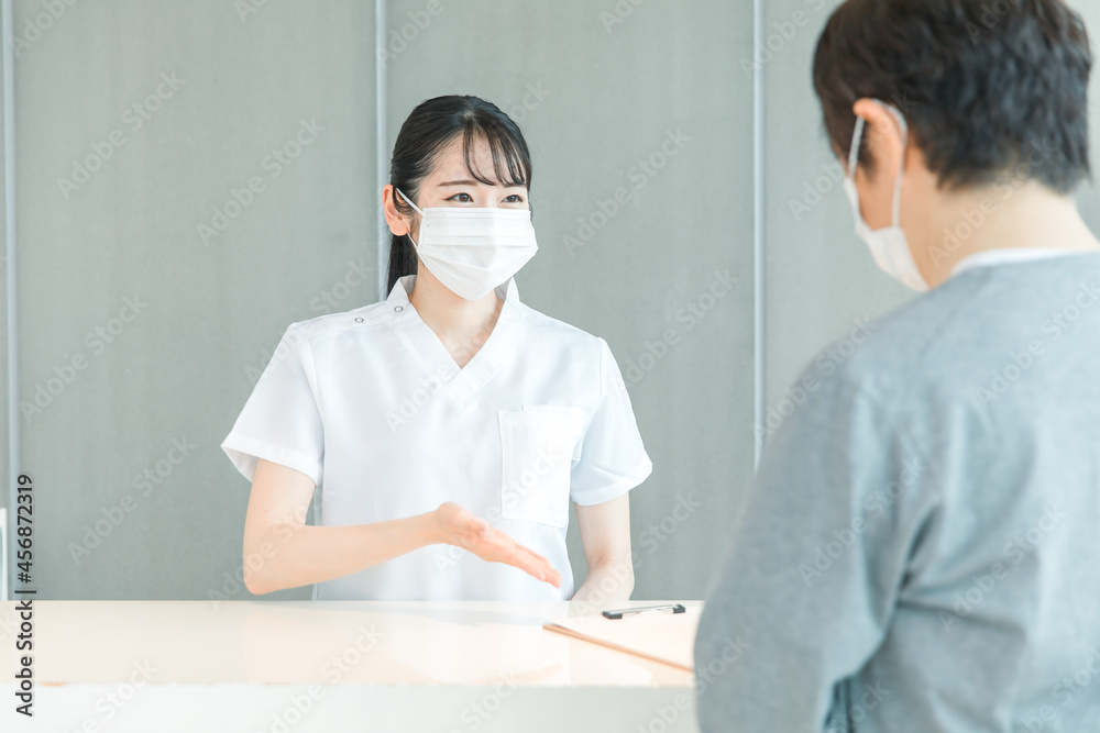 Fototapeta premium 受付にいる看護師と患者（マスク） 