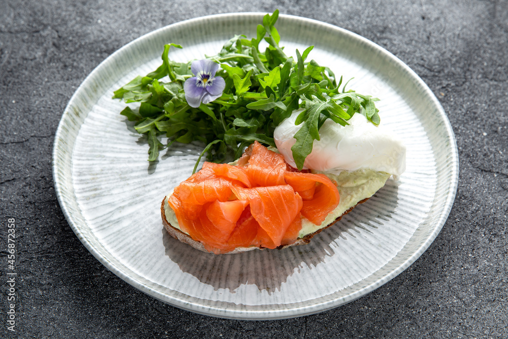 Bruschetta with salmon, poached egg and cheese. Ready menu for the restaurant. Neutral gray blue textured background Bruschetta with salmon, poached egg and cheese. Ready menu for the restaurant. Neutral gray blue textured background