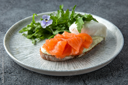 Bruschetta with salmon, poached egg and cheese. Ready menu for the restaurant. Neutral gray blue textured background