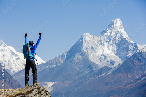 Hiker cheering elated and blissful with arms raised in the sky after hiking. Everest mountain on the backgroung - the world highest peak