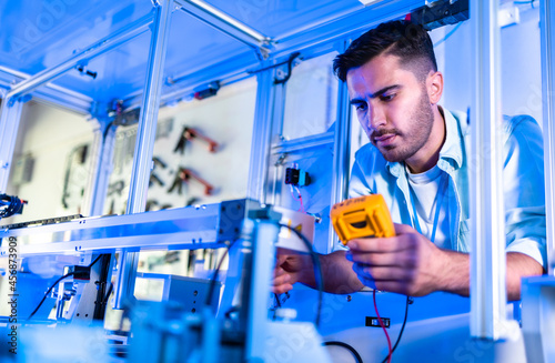 Engineers Maintenance Robot Arm at Lab. he are in a High Tech Research Laboratory with Modern Equipment. Technology and Innovation Concept.Professional Japanese Development Engineer is Testing .