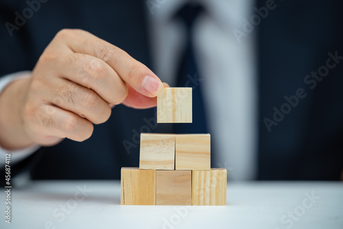 The hands of a male businessman who is stacking wooden blocks. Business concept.
