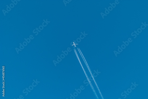Absolutely clear blue sky and a plane in the distance followed by an inversion white trail
