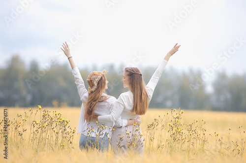 two girlfriends in an autumn field happiness / two young women hugging in a field, happiness friendship
