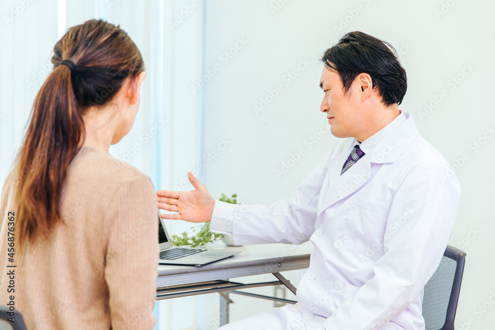 Obraz premium 診察する男性医師と女性患者（ノートパソコン） 