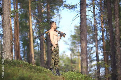 man goes hunting forest summer / landscape in the forest, huntsman with a hunting rifle hunts