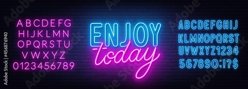Enjoy today neon lettering on brick wall background.