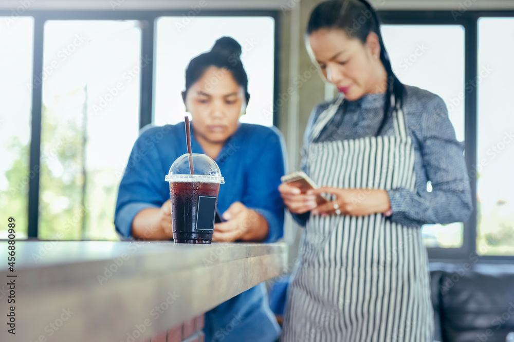 Black Ice Coffee Americano with Blurred Asian entrepreneur using a digital cellphone Black Ice Coffee Americano with Blurred Asian entrepreneur using a digital cellphone