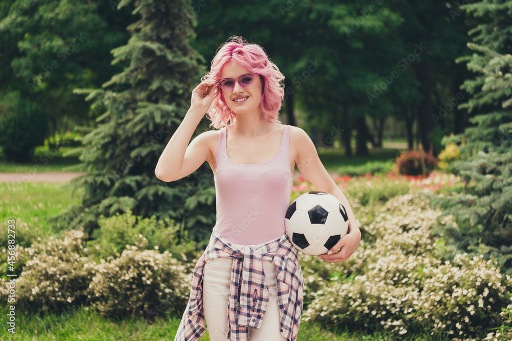 Fototapeta premium Photo of young sportive girl happy positive smile hold soccer ball player game park nature hand touch sunglass outdoors