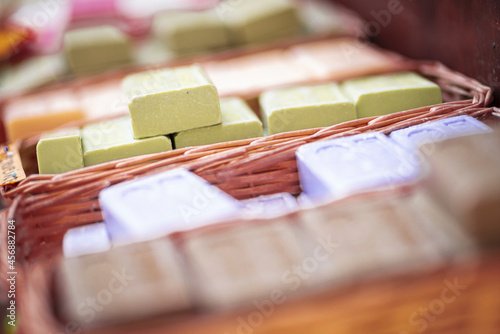 Stack of soap bars in abundance inside wicker basket. Fresh scented soap bars stack collection in basket at store or warehouse. Collection of lots of soap bars with different fragrance in basket